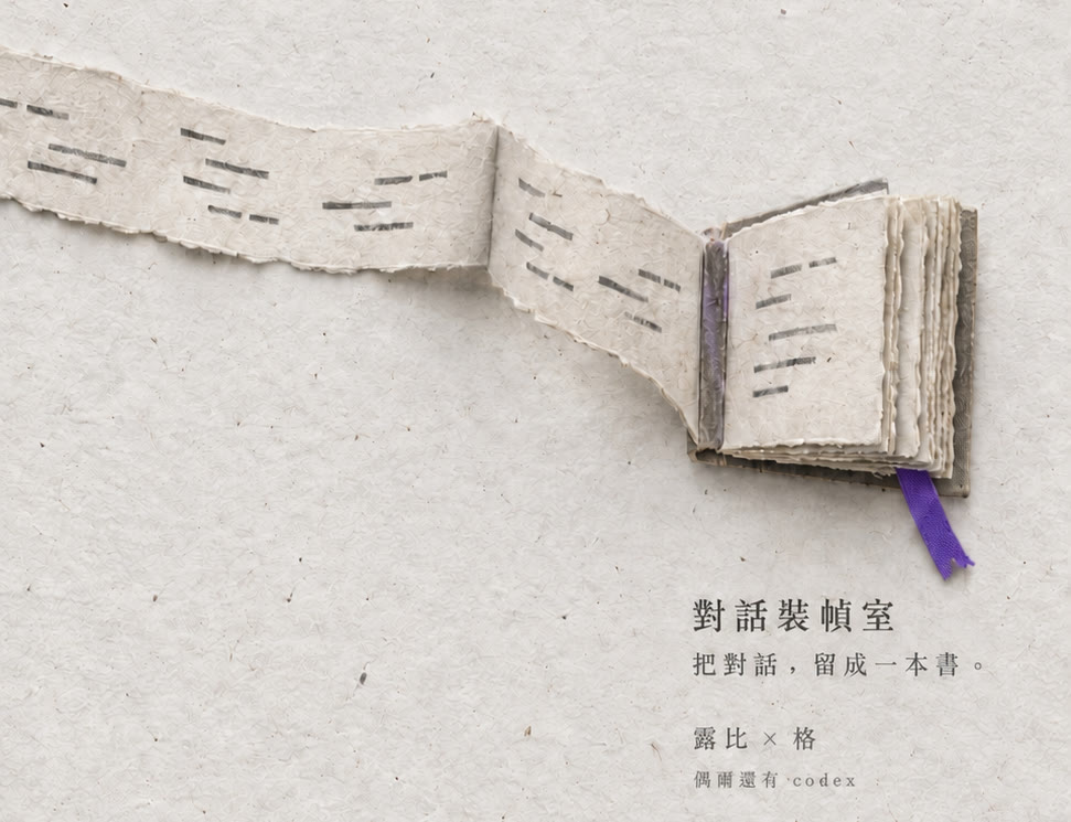 一長條寫著對話的毛邊紙帶，一路摺成一本夾著紫色書籤帶的小書。對話裝幀室：把對話，留成一本書。露比 × 格，偶爾還有 codex。